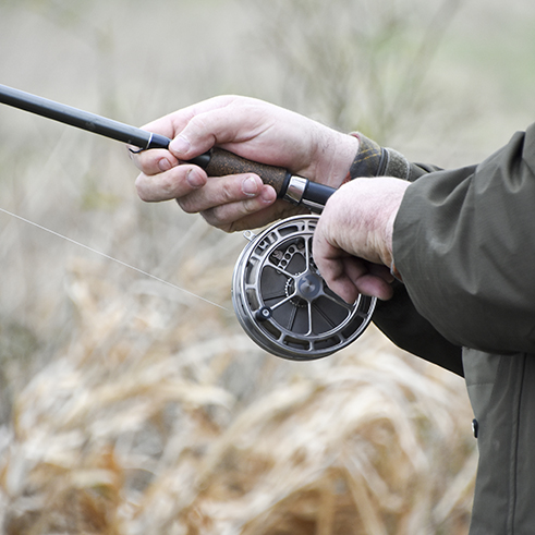 A person holding a fishing rod and reel