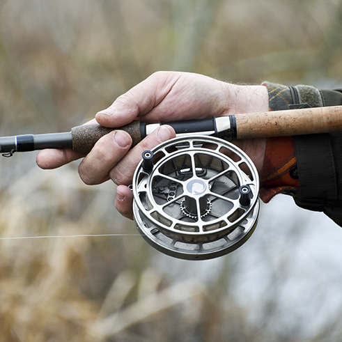 A person holding a fishing rod and reel